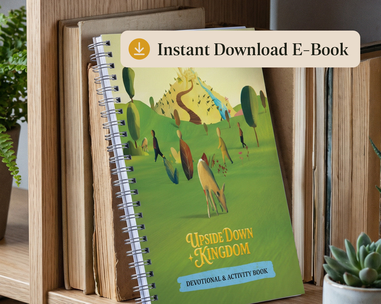 A spiral-bound devotional and activity book titled 'Upside Down Kingdom' leaning on a wooden bookshelf, with a beige banner overlay reading 'Instant Download E-Book' at the top. The cover features a colorful illustrated landscape with green hills, trees, and figures.